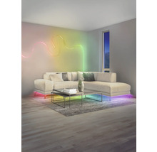 Modernes Wohnzimmer mit wellenförmigem LED-Lichtstreifen an der Wand, beleuchtetem Ecksofa und Couchtisch auf einem Teppich.