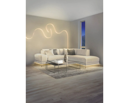 Modernes Wohnzimmer mit L-Sofa, dekorativem wellenförmigem LED-Wandlicht und indirekter LED-Bodenbeleuchtung unter dem Sofa.
