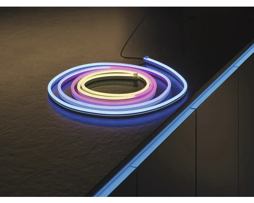 Flexibler LED-Neon-Strip, aufgerollt auf einer dunklen Fläche und als Akzentbeleuchtung an einer Möbelkante montiert.