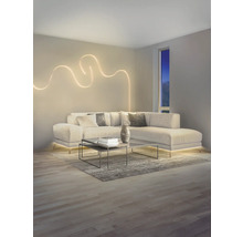 Modernes Wohnzimmer mit L-Sofa, dekorativem wellenförmigem LED-Wandlicht und indirekter LED-Bodenbeleuchtung unter dem Sofa.