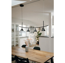 Moderne Pendelleuchte in Schwarz mit vier konischen Strahlern über einem massiven Holzesstisch in einem hellen skandinavisch eingerichteten Raum.