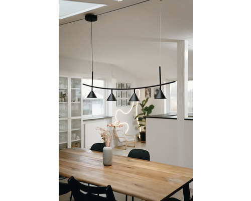 Moderne Pendelleuchte in Schwarz mit vier konischen Strahlern über einem massiven Holzesstisch in einem hellen skandinavisch eingerichteten Raum.