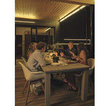 Vier Personen sitzen nachts an einem Holztisch auf einer Holzterrasse, beleuchtet durch LED-Lichtleisten an Decke und Wänden.