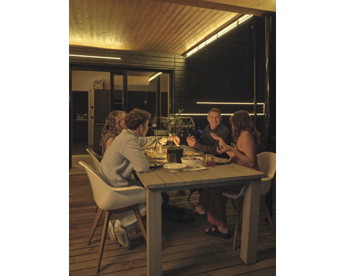 Vier Personen sitzen nachts an einem Holztisch auf einer Holzterrasse, beleuchtet durch LED-Lichtleisten an Decke und Wänden.