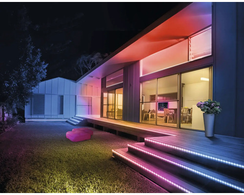 Moderne Hausfassade bei Nacht mit bunten LED-Streifen an Treppen und Dachkante für atmosphärische Außenbeleuchtung.