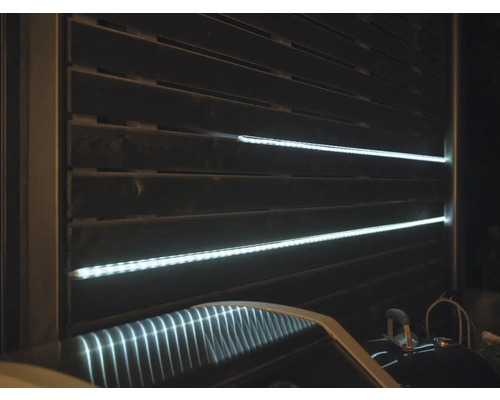 Sichtschutzzaun mit horizontalen Lamellen und integrierten LED-Lichtleisten.