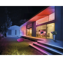 Moderne Hausfassade bei Nacht mit bunten LED-Streifen an Treppen und Dachkante für atmosphärische Außenbeleuchtung.