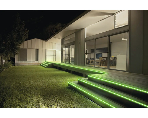 Außenbeleuchtung einer modernen Terrasse bei Nacht mit grünen LED Streifen an den hölzernen Treppenstufen.