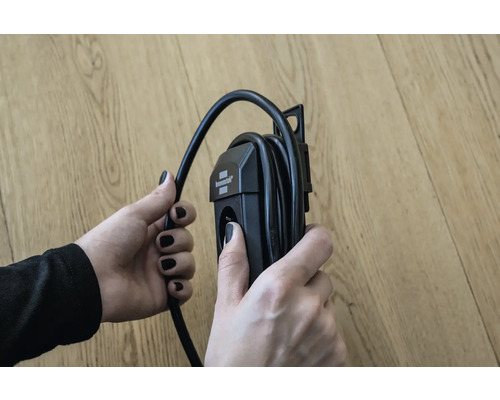 Eine Person hält eine Kabeltrommel in der Hand.