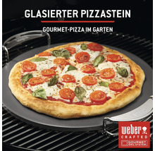 Glasierter Pizzastein mit zubereiteter Pizza auf einem Grill
