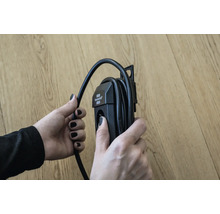 Eine Person hält eine Kabeltrommel in der Hand.