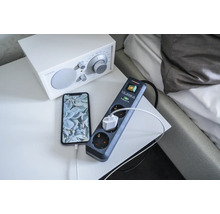 Steckdosenleiste mit Überspannungsschutz und angeschlossenem Telefon auf einem Nachttisch