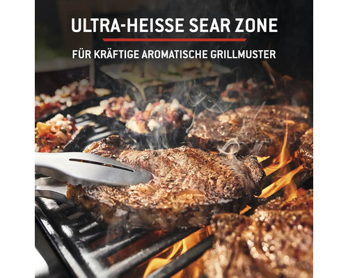 Grill mit Fleisch auf dem Rost und Grillzange