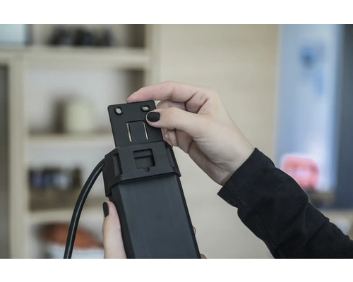 Person montiert eine Halterung an einem Rollladenmotor.