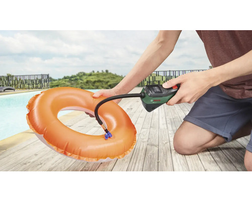 Eine Person pumpt einen Schwimmreifen mit einer Bosch Luftpumpe neben einem Pool auf.