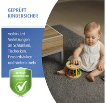 Kleinkind spielt mit einem Spielzeug neben einem Tisch auf einem Teppich. Kindersicherheitsprüfung.