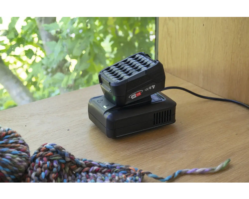 Akkupack und Ladegerät für Elektrowerkzeuge auf einem Tisch.