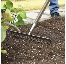 Gartenrechen mit Holzgriff im Einsatz auf Gartenerde.