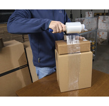 Mann verpackt Kartons mit Stretchfolie