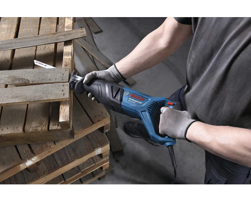 Bosch Professional Säbelsäge GSA 12-30 beim Zersägen einer Holzpalette durch eine Person mit Arbeitshandschuhen.