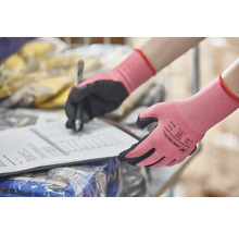 Hände mit Arbeitshandschuhen schreiben auf ein Dokument