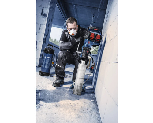 Handwerker bedient ein Bosch Kernbohrgerät mit Diamantbohrkrone und Bosch Wasserdruckbehälter auf einer Baustelle.