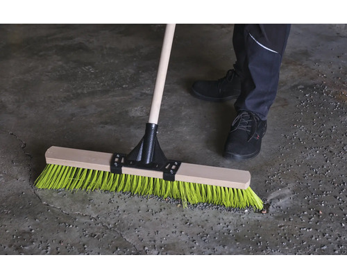 Besen mit Holzstiel und farbigen Borsten im Einsatz