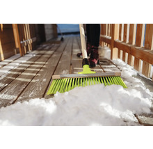 Schneeräumen mit einem Besen auf einer Holzterrasse