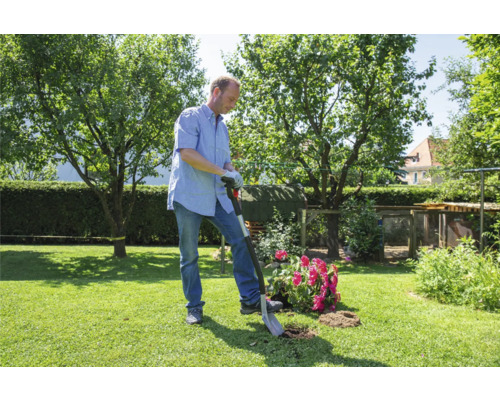 Mann pflanzt Blumen mit einem Spaten im Garten.