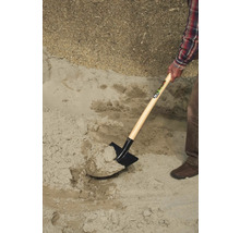 Eine Person schaufelt Sand mit einem Spaten.
