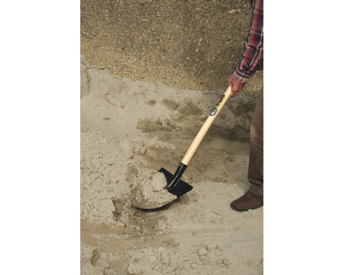 Eine Person schaufelt Sand mit einem Spaten.