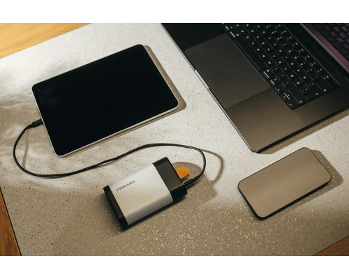 Elektronische Geräte auf einem Tisch: Tablet, Laptop, Smartphone und ein Fiskars Werkzeugschärfer.