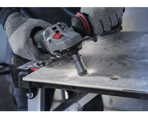 Bediener bohrt mit einem Winkelschleifer ein Loch in eine Fliese.