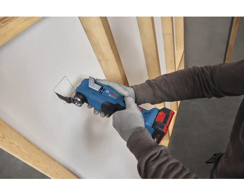 Akku-Multifunktionswerkzeug Bosch Professional beim Ausschneiden einer Öffnung in einer Gipskartonplatte zwischen Holzständern.