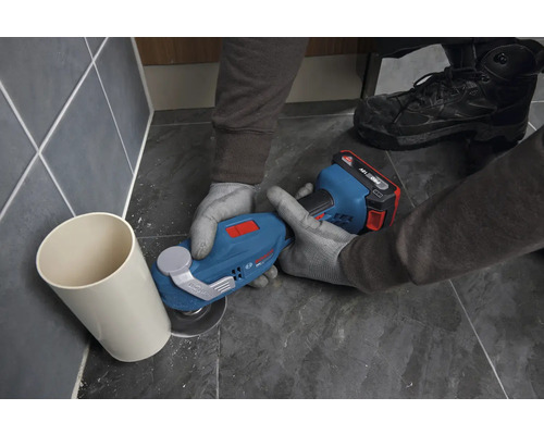Bosch Akku-Multitool beim bündigen Abschneiden eines Kunststoffrohrs auf Bodenfliesen.