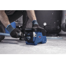 Eine Person schließt einen Schlauch mit Metallkupplung an eine Bosch Akku-Wasserpumpe an.