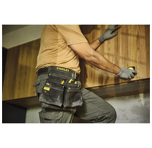 Handwerker mit Werkzeugtasche und Maßband bei der Montage von Holzschränken