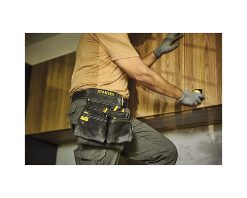 Handwerker mit Werkzeugtasche und Maßband bei der Montage von Holzschränken