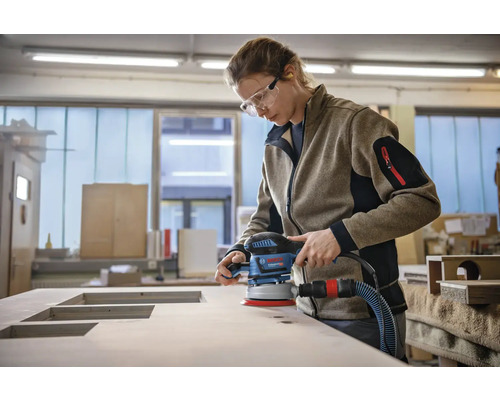 Frau schleift Holzplatte mit einem Exzenterschleifer
