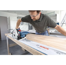 Handwerker sägt Holzplatte mit einer Bosch Tauchsäge und Führungsschiene.