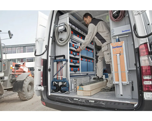Ein Handwerker ordnet Werkzeug in einem Sortimo-Regalsystem in einem Lieferwagen, um Ordnung und Effizienz zu gewährleisten.