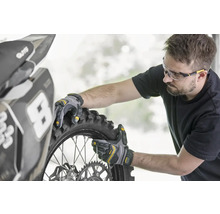 Eine Person montiert mit Arbeitshandschuhen einen Motorradreifen.