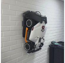 Zusammengeklappter Mähroboter an einer Wandhalterung.
