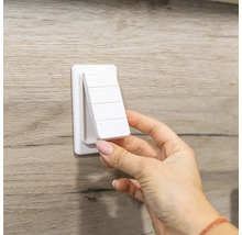 Weiße magnetische Fernbedienung für Smart Home Wandschalter mit vier Tasten wird von der Wandhalterung abgenommen.
