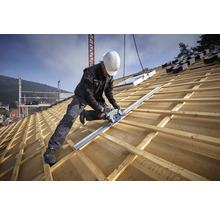 Handwerker auf einem Holzdach nutzt eine Handkreissäge mit Führungsschiene zum Zuschneiden von Dachlatten.