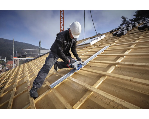 Handwerker auf einem Holzdach nutzt eine Handkreissäge mit Führungsschiene zum Zuschneiden von Dachlatten.