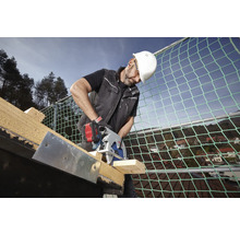 Handwerker mit weißem Helm schneidet mit einer Bosch Akku-Kreissäge Holz auf einem Dach mit Sicherheitsnetz.