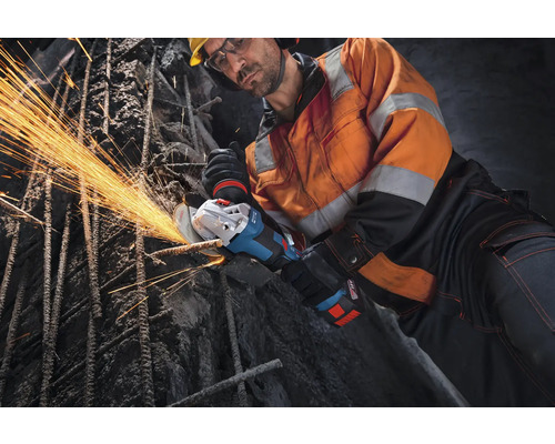 Bauarbeiter verwendet einen Akku-Winkelschleifer zum Schneiden von Bewehrungsstahl auf einer Baustelle mit Funkenflug.
