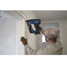 Handwerker befestigt eine Holzleiste an einer Türzarge mit einem Bosch Professional Akku-Nagler im Innenausbau.