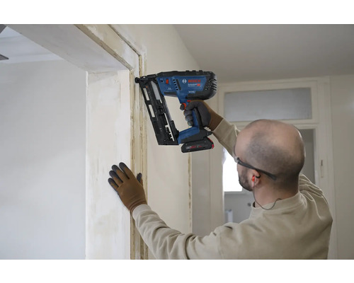 Handwerker befestigt eine Holzleiste an einer Türzarge mit einem Bosch Professional Akku-Nagler im Innenausbau.